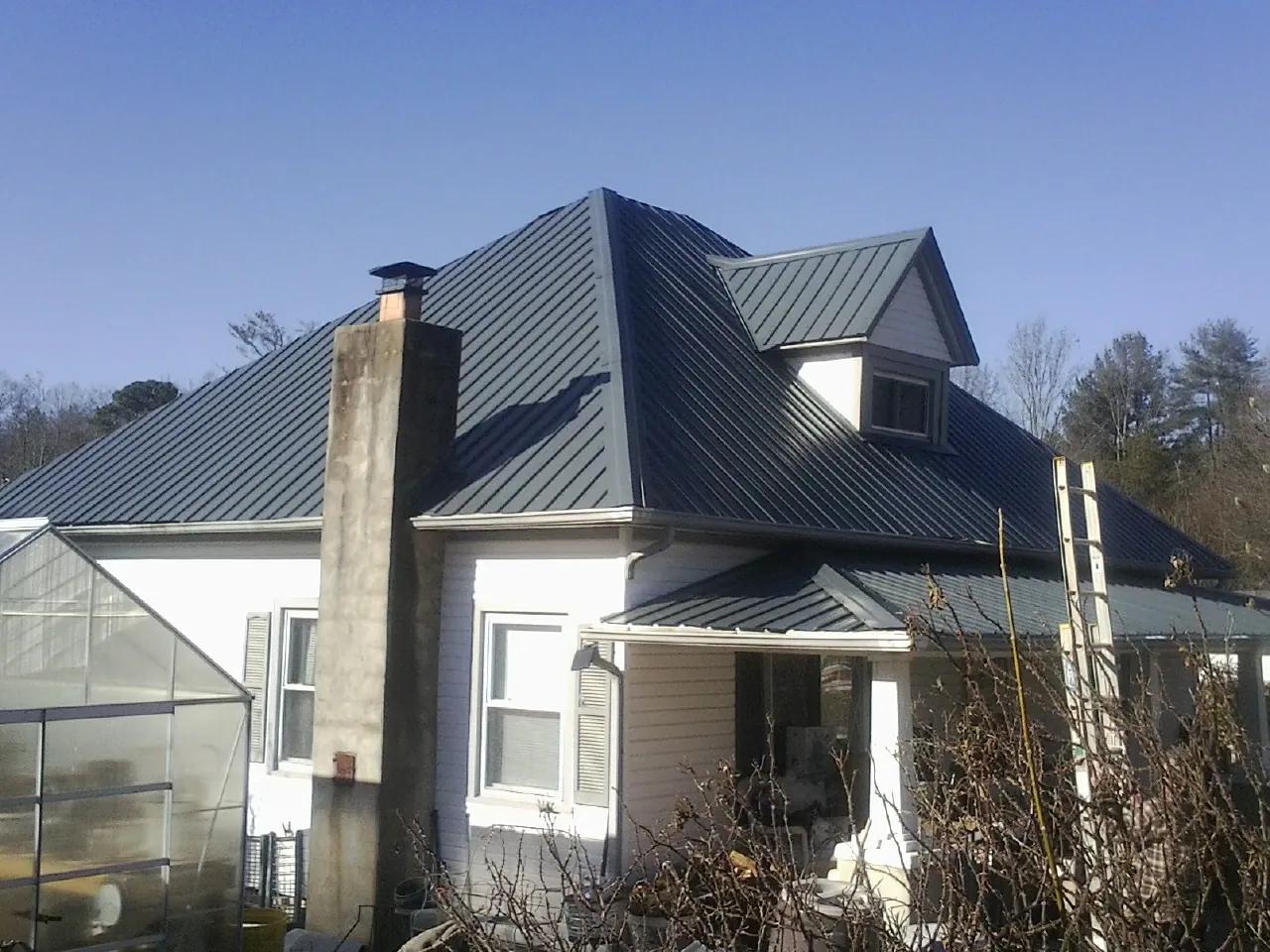 Dark blue standing seam metal roof on a white farmhouse with dormer — Slate & Tile Roof Repair by Roofing Brothers in Verdi