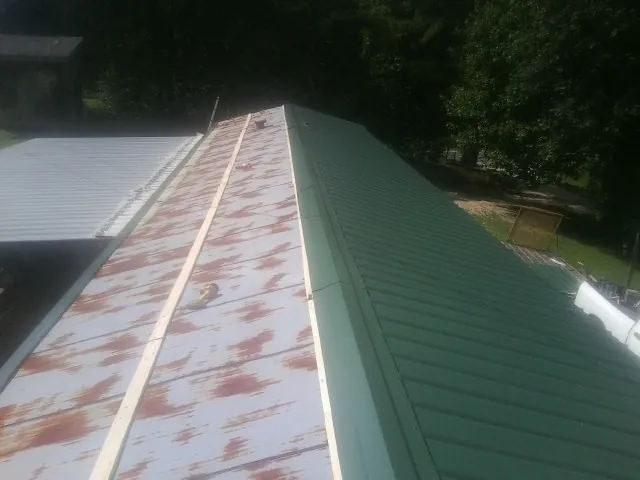 Old rusted panels beside newly installed green metal roofing — Wind Damage Roof Repair by Roofing Brothers in Verdi