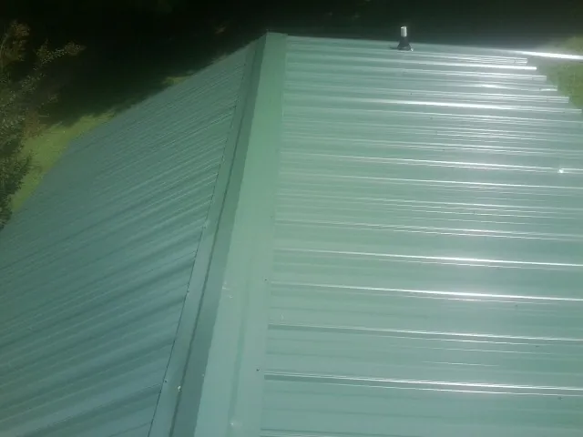 New green metal panels meeting at the ridge of a roof — Flat Roof Repair work by our crew in Verdi