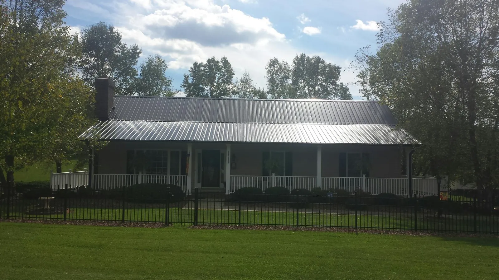 Gray metal roof on a brick ranch with a full width front porch — Gutter Guard Installation work by our crew in Verdi