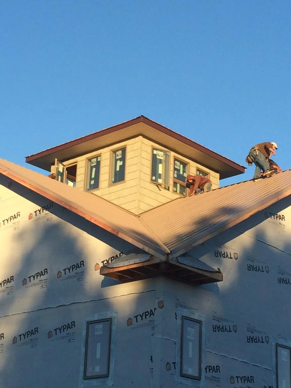 Roofers working around a rooftop cupola on a new metal roof at sunset — Roof Waterproofing in Verdi by Roofing Brothers